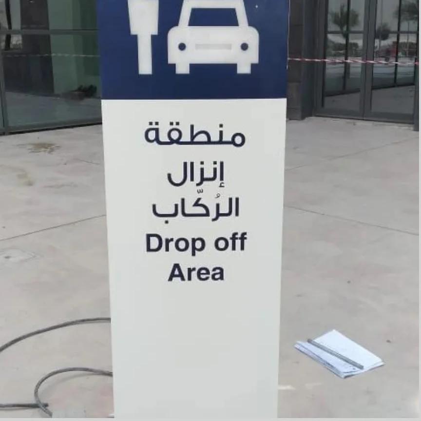Bilingual drop-off zone wayfinding sign mounted on marble